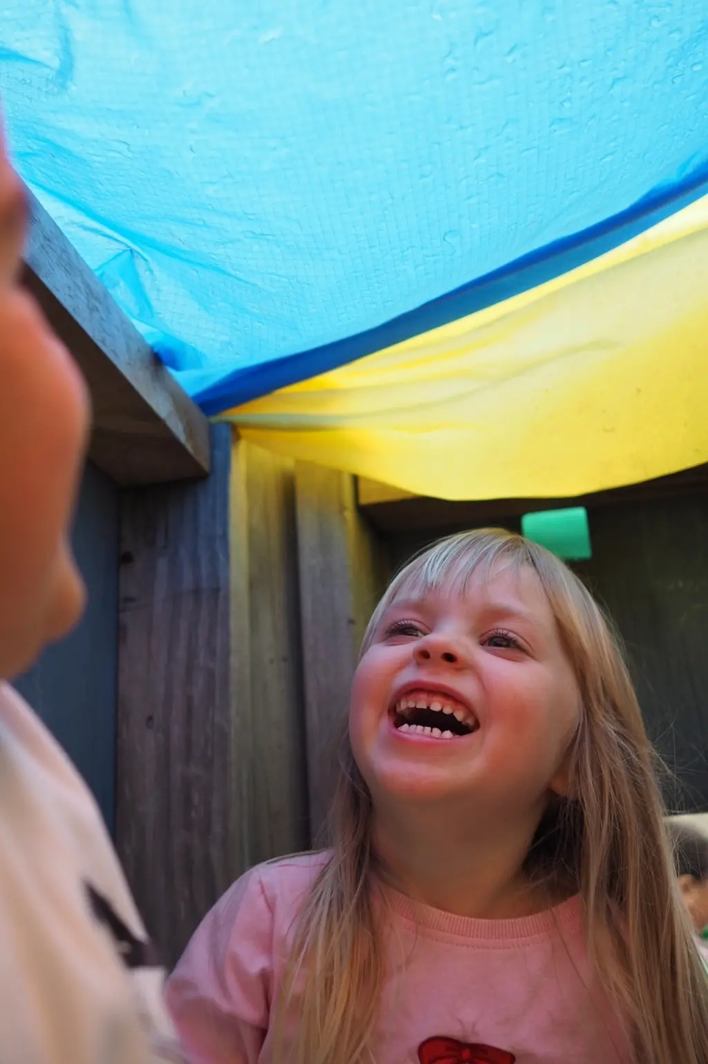 Child laughing with a friend inside an outdoor play space