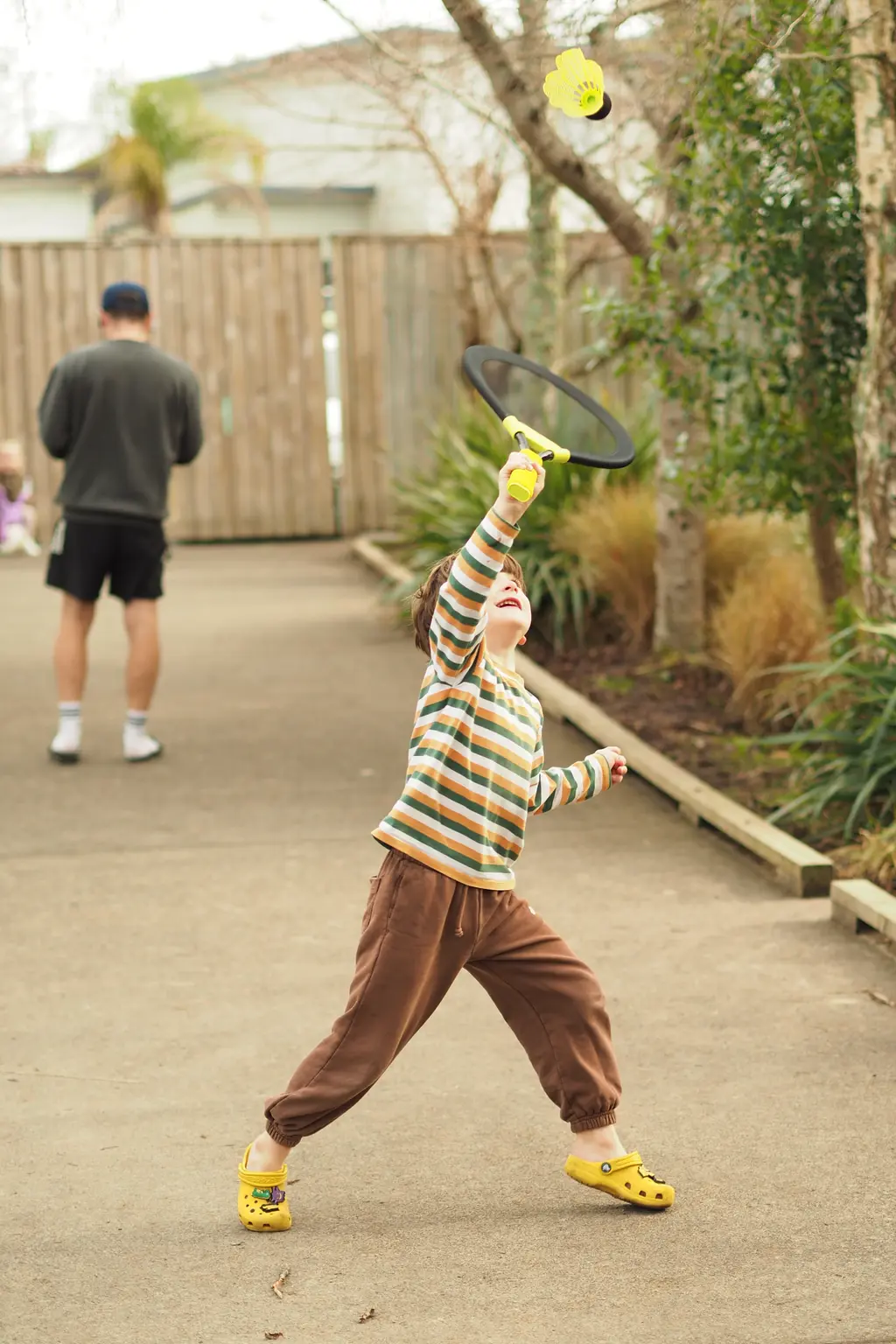 Child reaching to hit a shuttlecock outdoors
