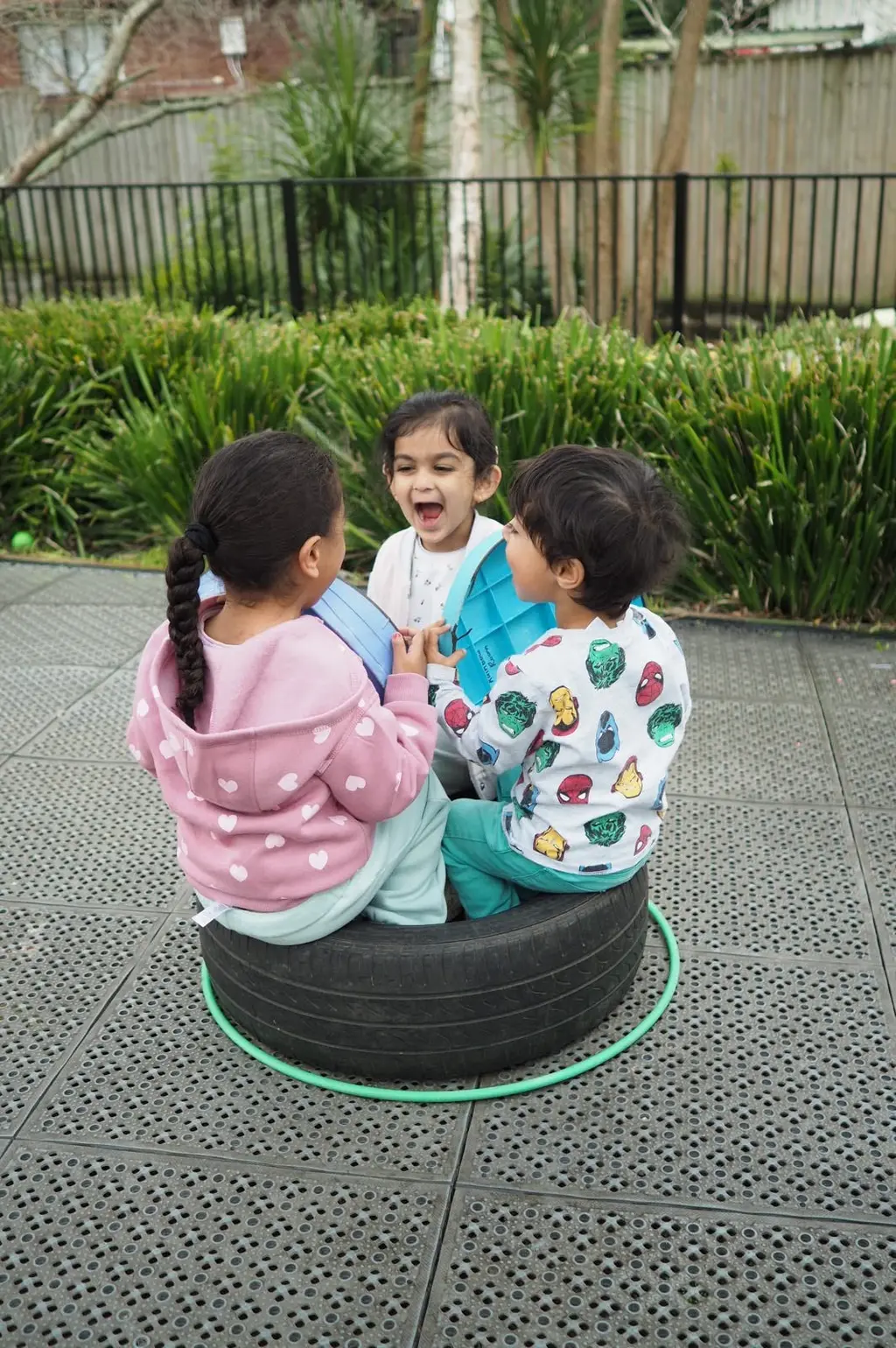 Three children laughing and playing together outdoors